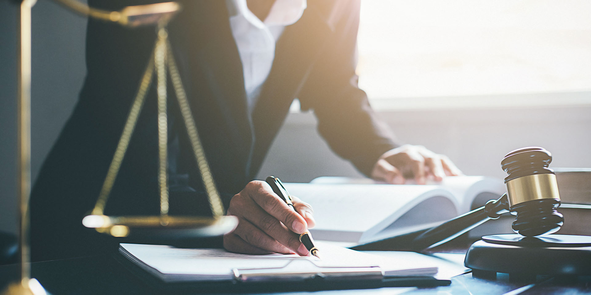 Justice and Law concept. Legal counsel presents to the client a signed contract with gavel and legal law or legal having team meeting at law firm in background